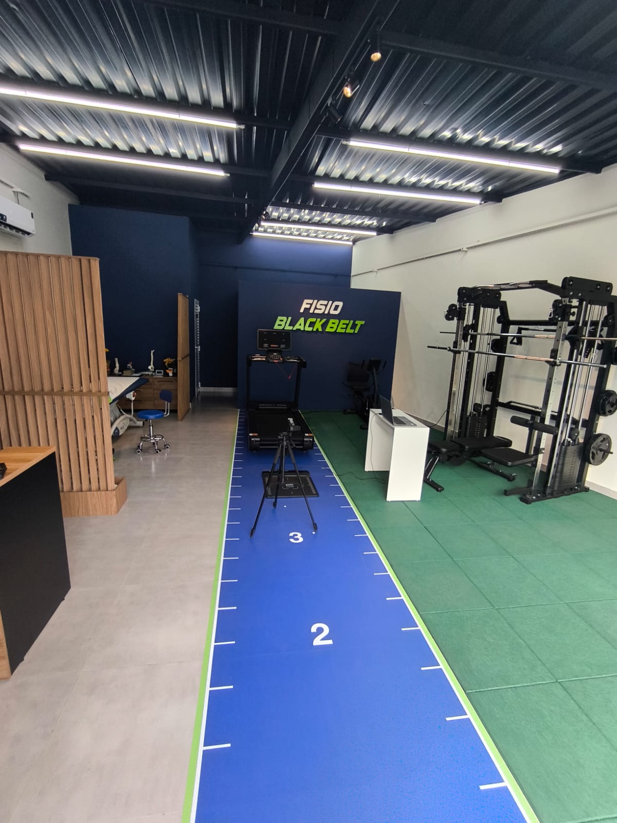 Vista do espaço de atendimento do Studio Fisio Black Belt, com esteira e equipamentos de movimento
