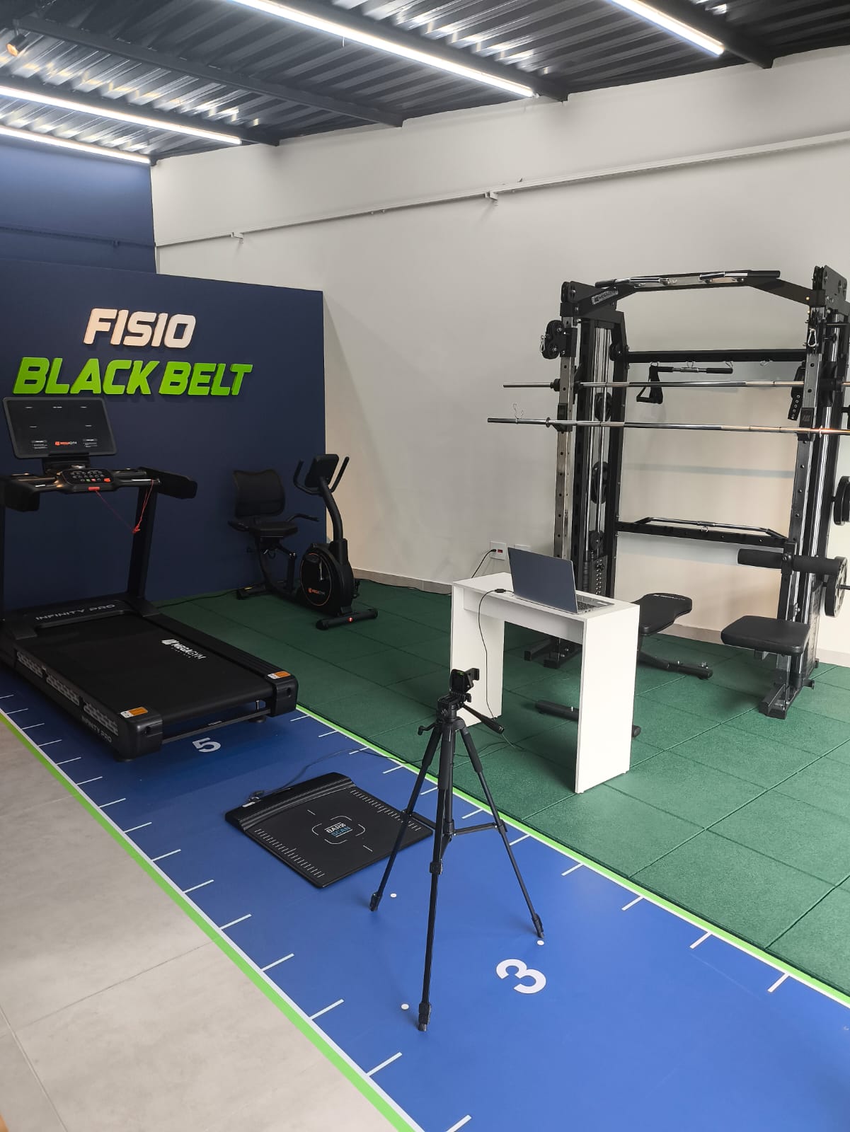 Sala de avaliação do Studio, com esteira profissional, marcações no piso e tatame
